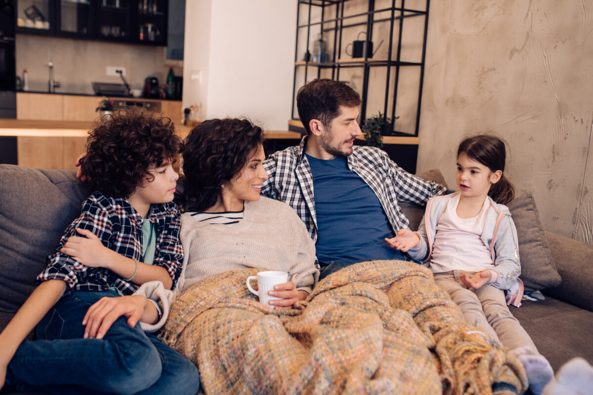 Young couple and their two kids relaxing on the sofa
