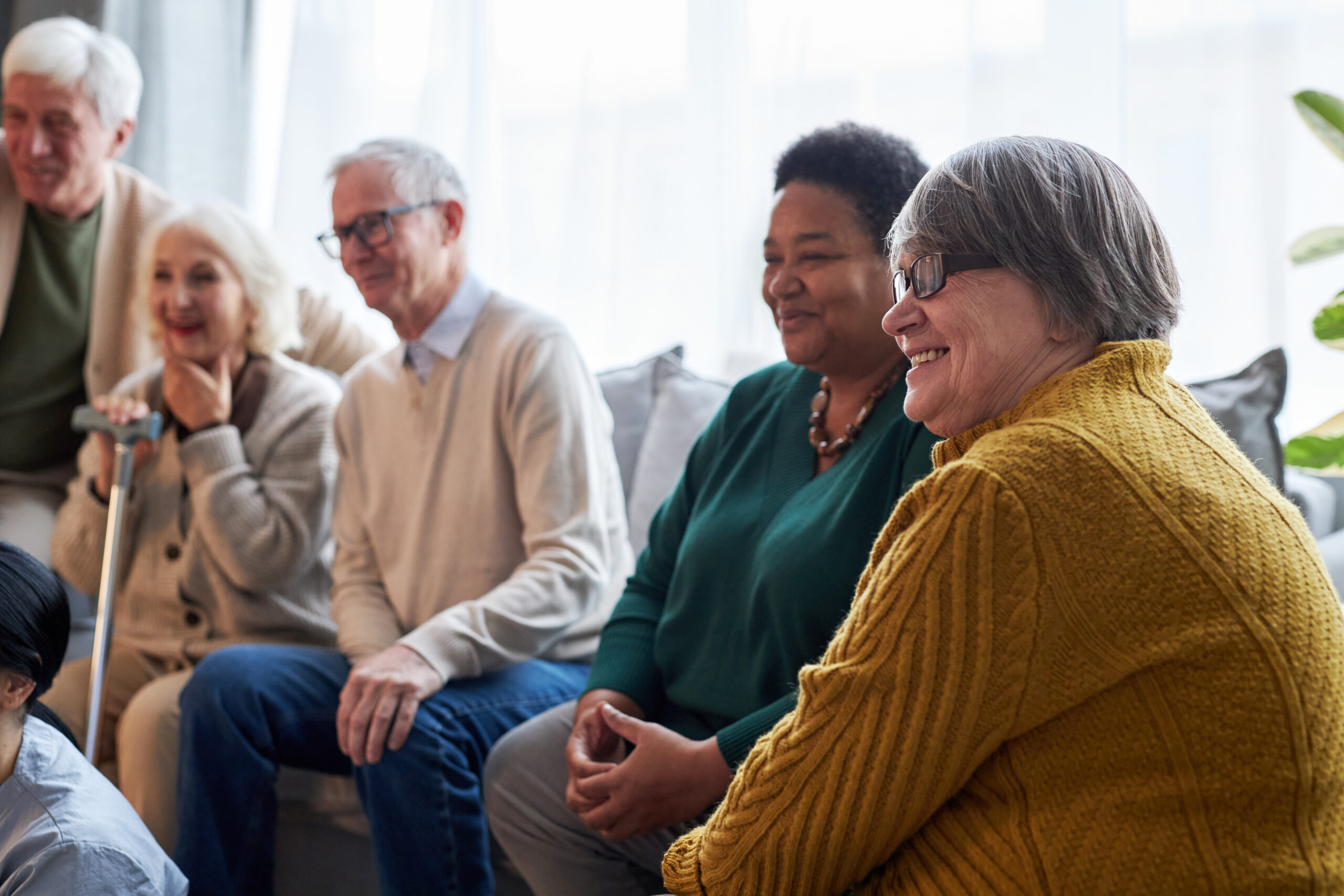 Senior people watching TV while sitting in row in retirement home facility